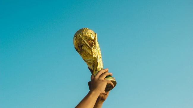 world cup trophy being held with a clear sky background